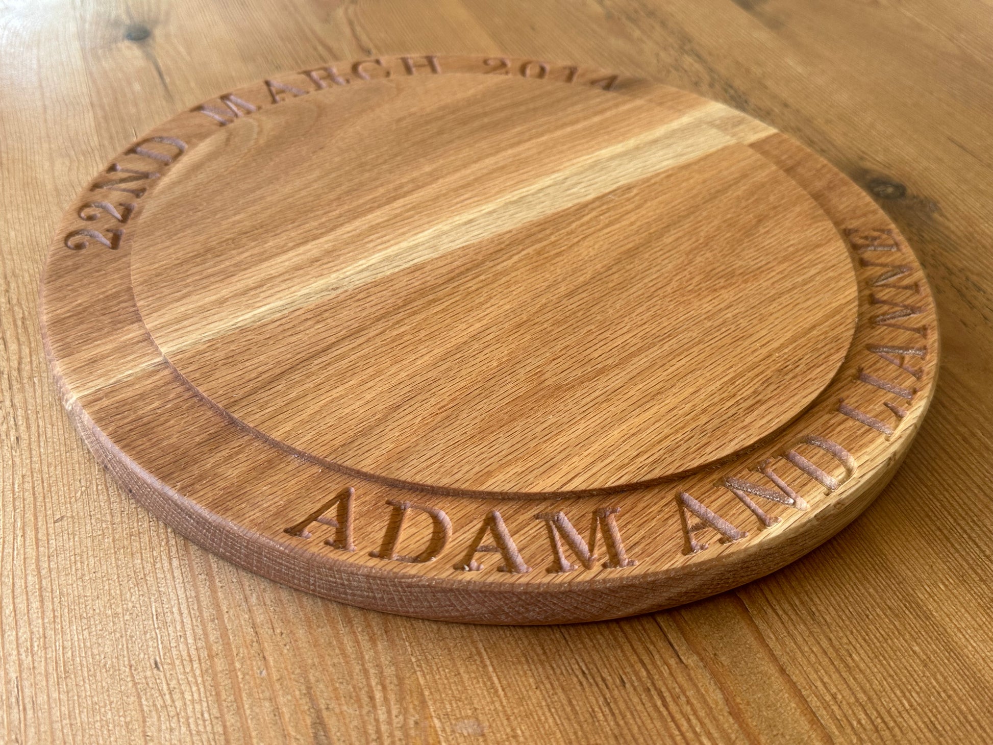 Angled view of a custom oak cake stand engraved with “22ND MARCH 2014” and “ADAM AND LIANNE,” highlighting its stepped design and fine craftsmanship.