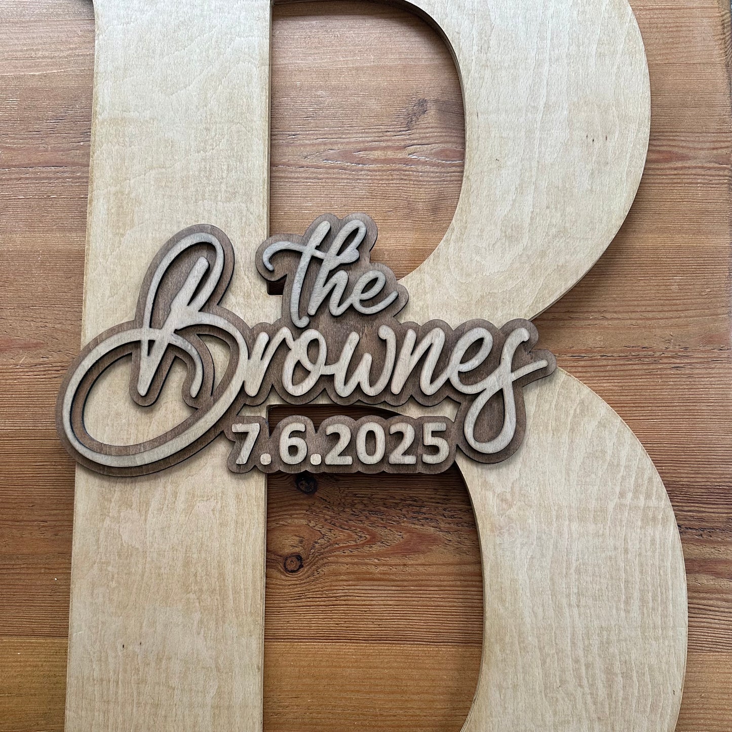 Close-up of a natural wood guestbook letter “B” featuring layered 3D engraving with “The Brownes – 7.6.2025.”