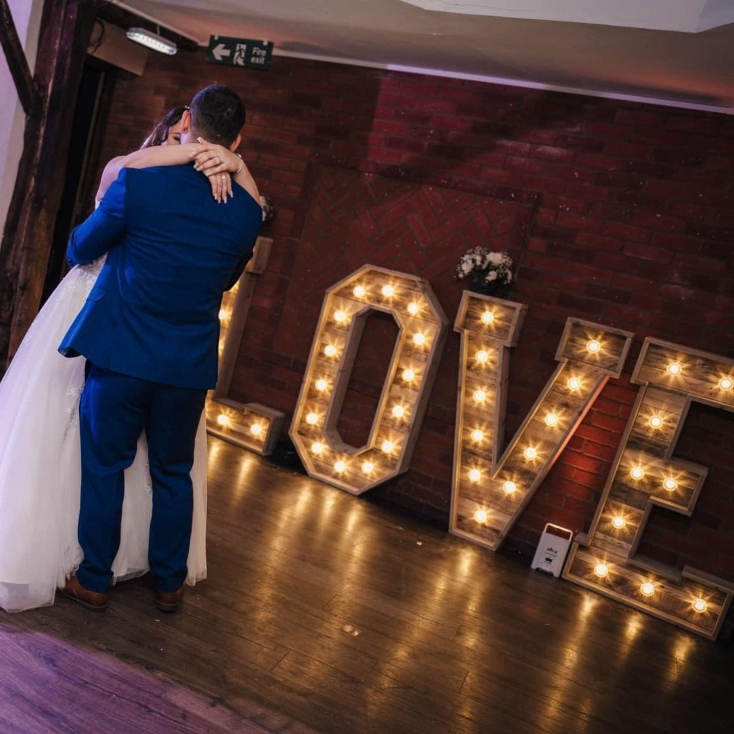 Bride and groom’s first dance with lit LOVE letters in the background — a magical wedding moment.