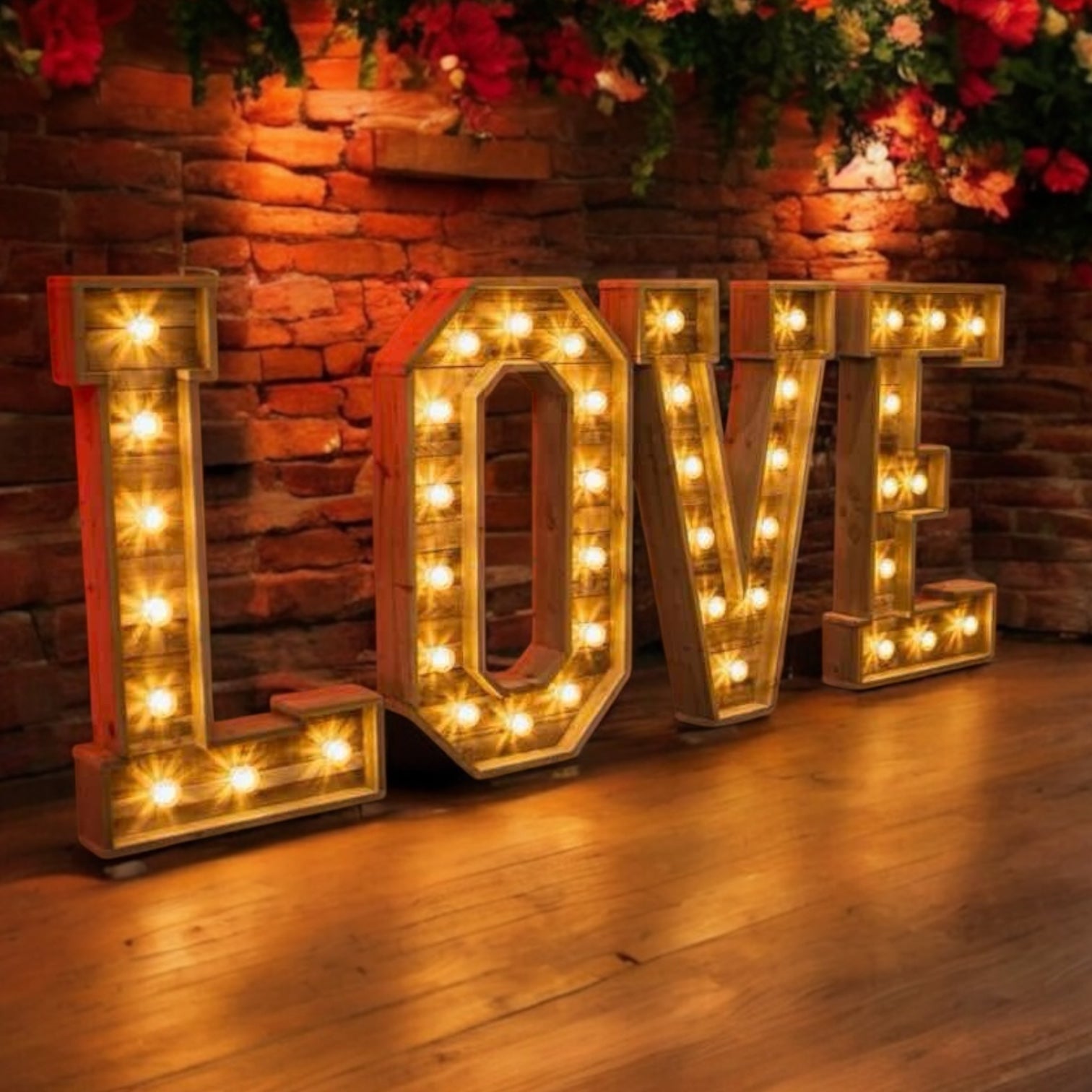 Wooden LOVE letters with warm bulbs in front of a rustic red brick wall — romantic evening setting.