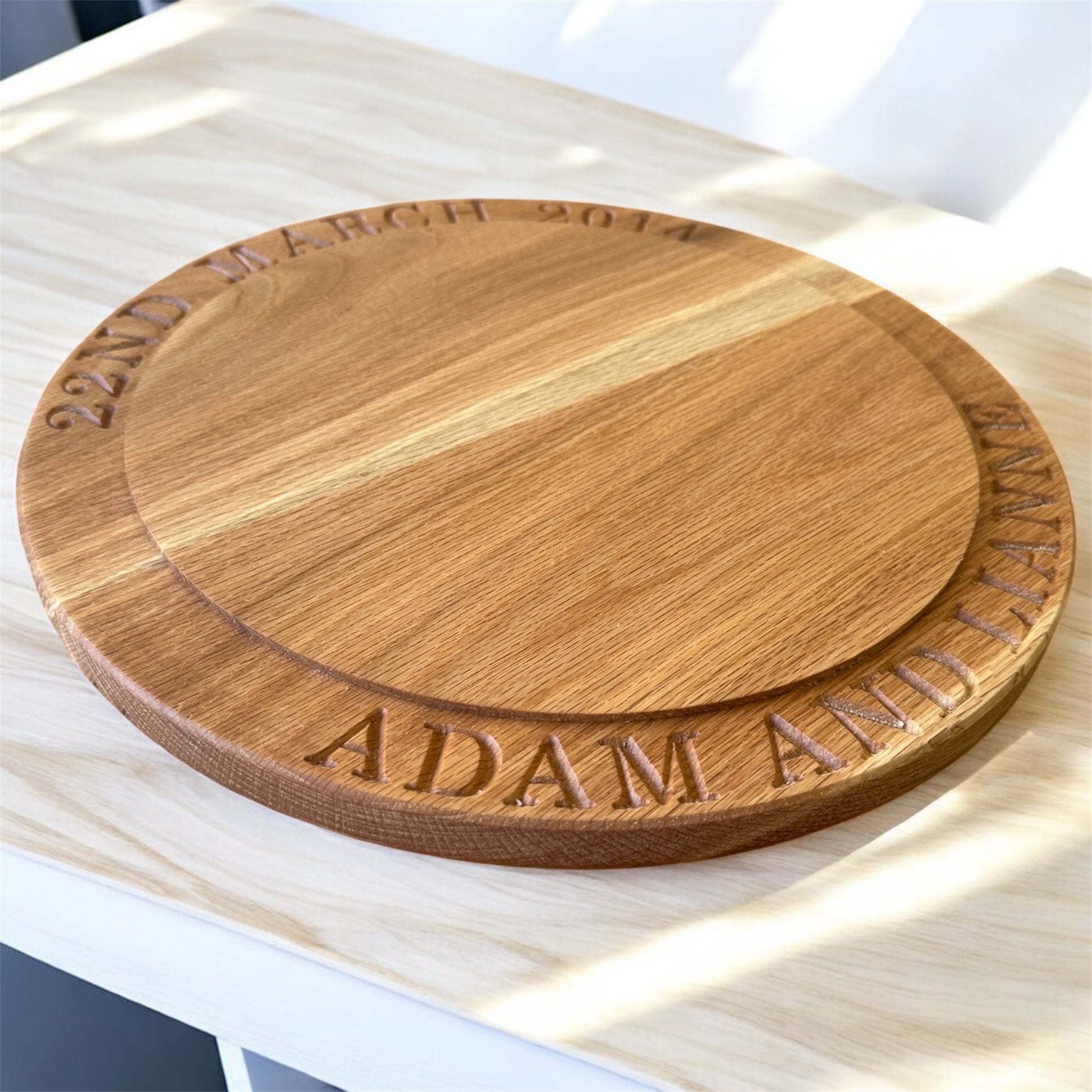 Personalised oak cake stand engraved with “22nd March 2014” and “Adam and Lianne,” showing natural wood grain and circular step-down design.