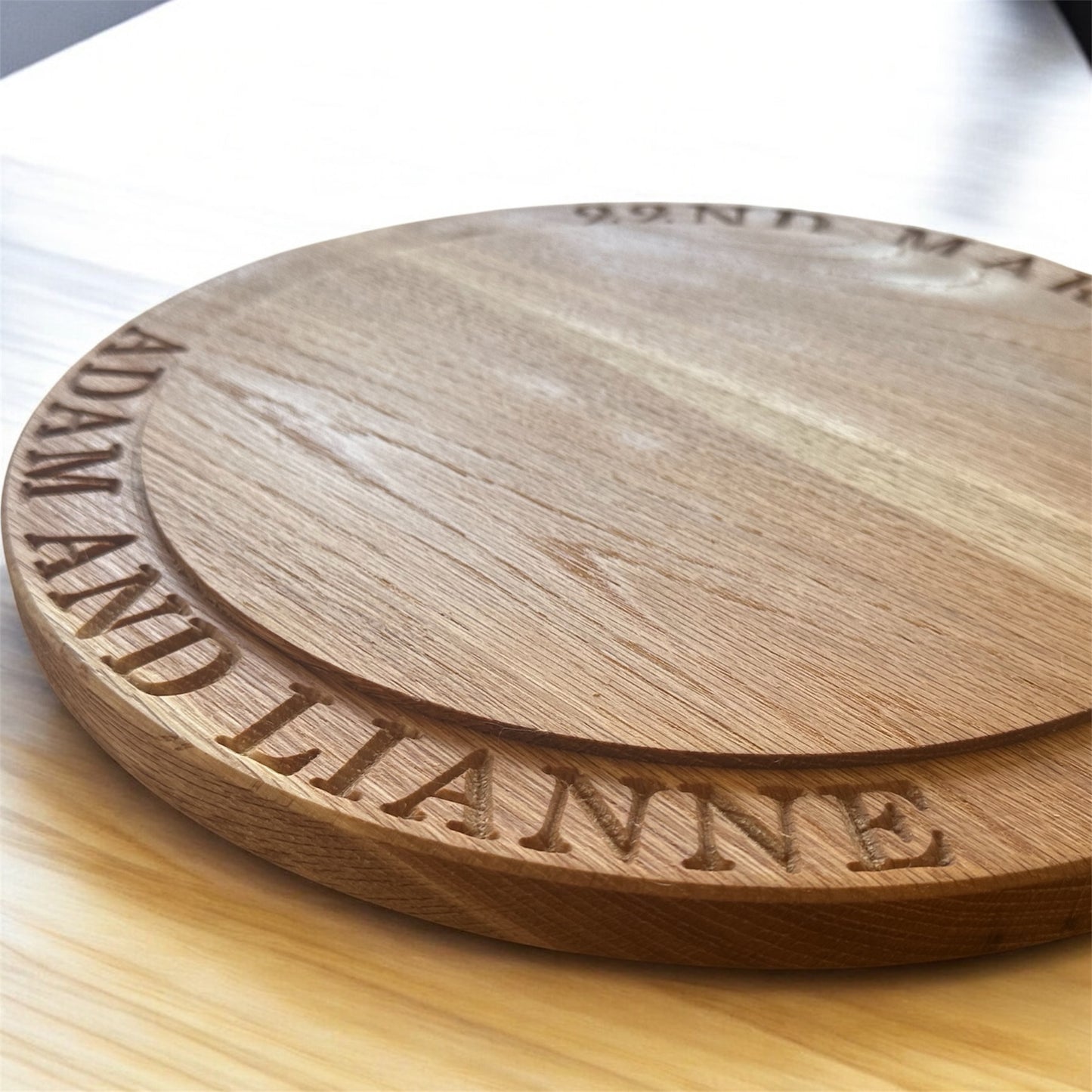 Side view of a handcrafted oak wedding cake stand featuring engraved text “Adam and Lianne” along the stepped border.